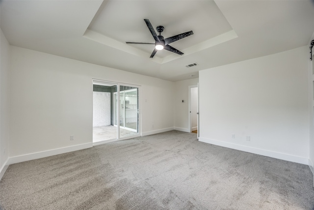 empty room featuring carpet floors, a tray ceiling, and ceiling fan