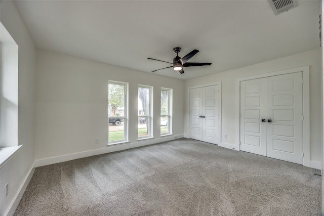 unfurnished bedroom with carpet floors, two closets, and ceiling fan