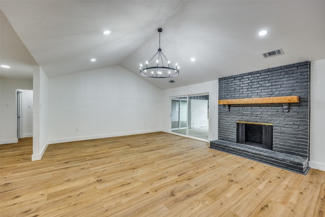 unfurnished living room featuring light wood-type flooring, a brick fireplace, lofted ceiling, and a notable chandelier