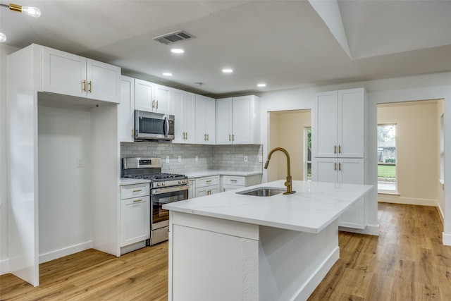 kitchen featuring appliances with stainless steel finishes, an island with sink, white cabinetry, and sink