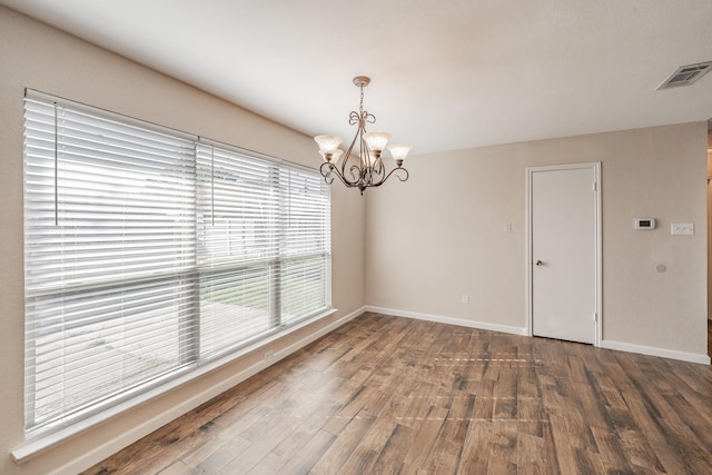 empty room with an inviting chandelier and wood-type flooring