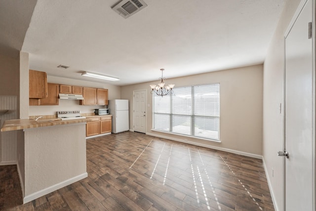 kitchen with range, a chandelier, white refrigerator, dark hardwood / wood-style flooring, and kitchen peninsula