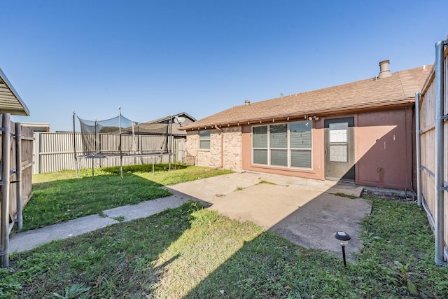 back of house with a lawn, a patio area, and a trampoline