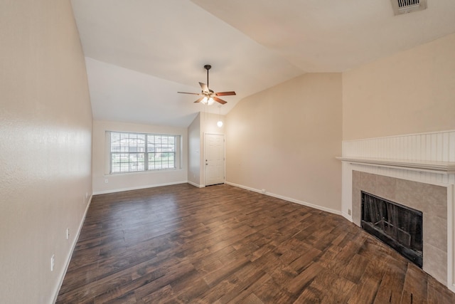 unfurnished living room with a tile fireplace, vaulted ceiling, dark wood-type flooring, and ceiling fan