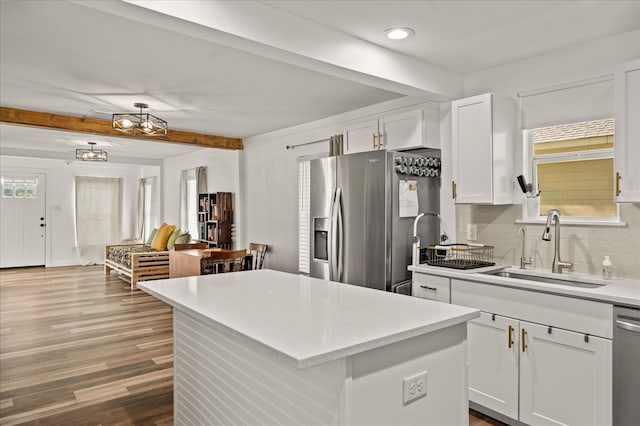 kitchen featuring white cabinetry, appliances with stainless steel finishes, backsplash, wood-type flooring, and a kitchen island