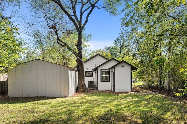 view of outbuilding with central AC unit and a yard