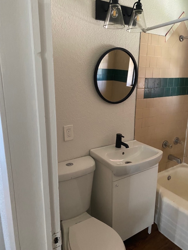 full bathroom featuring vanity, tiled shower / bath, hardwood / wood-style flooring, and toilet