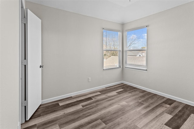 spare room with dark wood-style flooring and baseboards