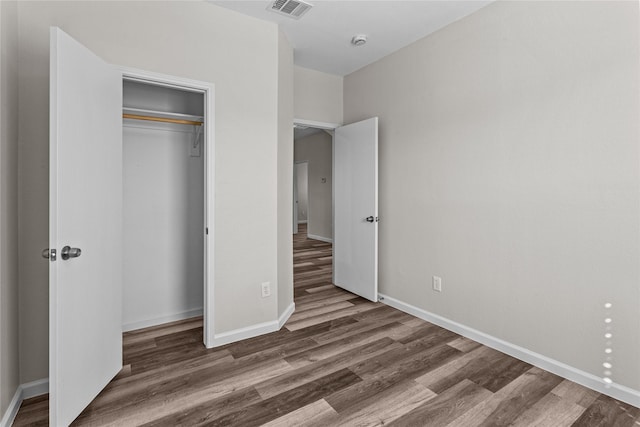 unfurnished bedroom featuring baseboards, a closet, visible vents, and dark wood-type flooring