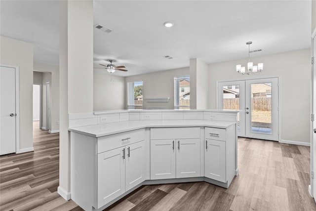 kitchen featuring white cabinets, a peninsula, visible vents, and light countertops