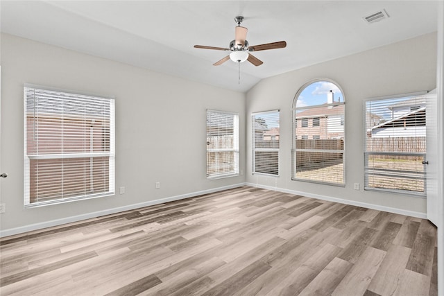 spare room with visible vents, baseboards, a ceiling fan, light wood-style flooring, and vaulted ceiling