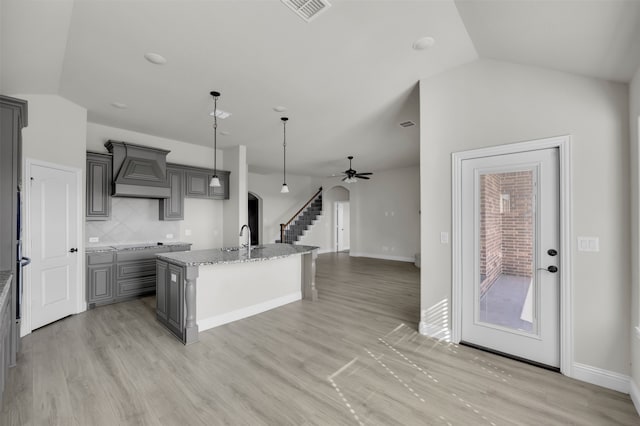 kitchen with gray cabinetry, a kitchen island with sink, ceiling fan, and lofted ceiling