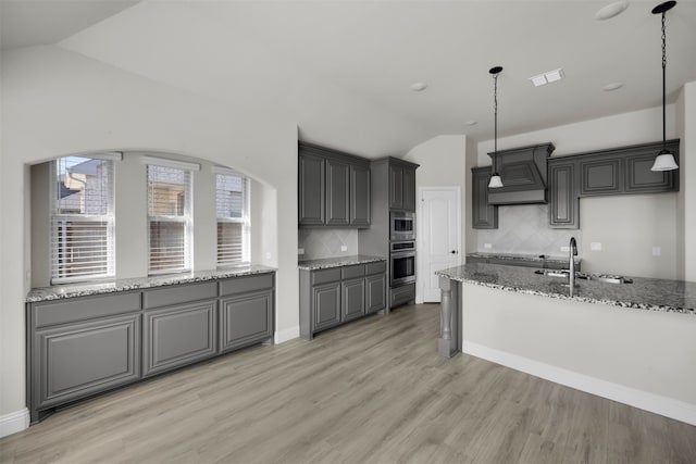 kitchen featuring custom range hood, pendant lighting, vaulted ceiling, and appliances with stainless steel finishes