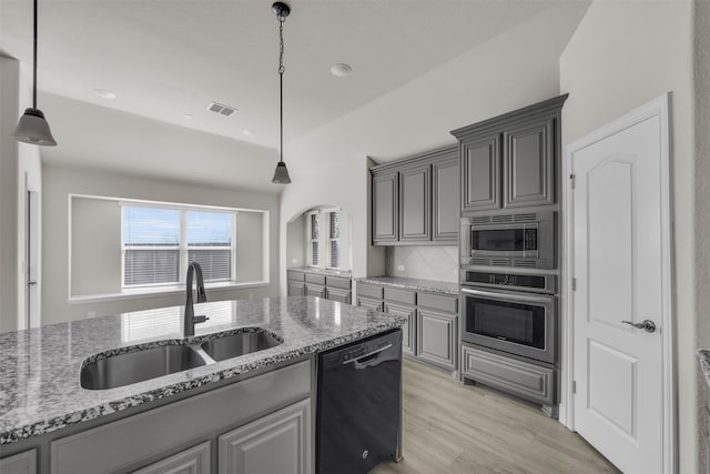 kitchen featuring pendant lighting, sink, light hardwood / wood-style flooring, light stone countertops, and appliances with stainless steel finishes