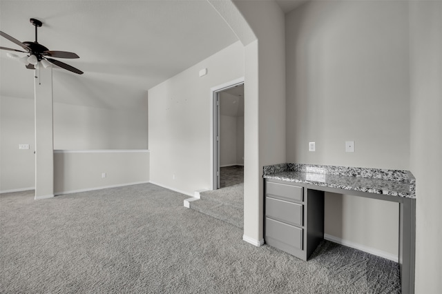 interior space with carpet flooring, built in desk, and ceiling fan