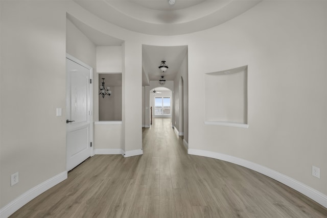 hall featuring light wood-type flooring and a notable chandelier