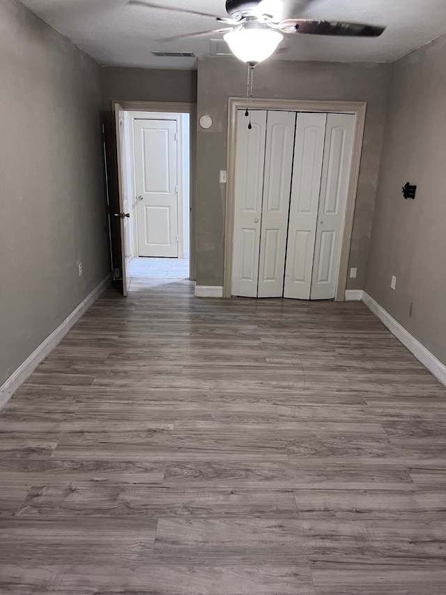 unfurnished bedroom featuring light wood-type flooring, ceiling fan, and a closet