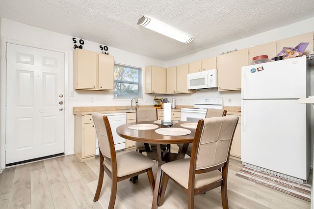 kitchen with cream cabinetry, light hardwood / wood-style flooring, a textured ceiling, and white appliances