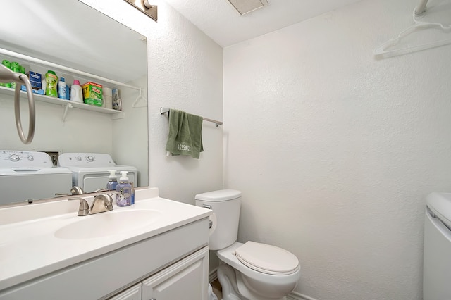 bathroom featuring washer and clothes dryer, vanity, and toilet