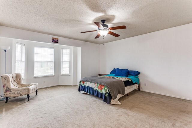 carpeted bedroom featuring ceiling fan and a textured ceiling