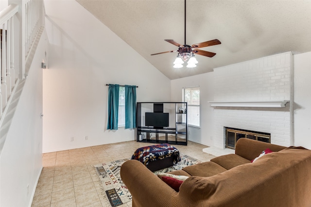 living room with a brick fireplace, a textured ceiling, light tile patterned floors, high vaulted ceiling, and ceiling fan