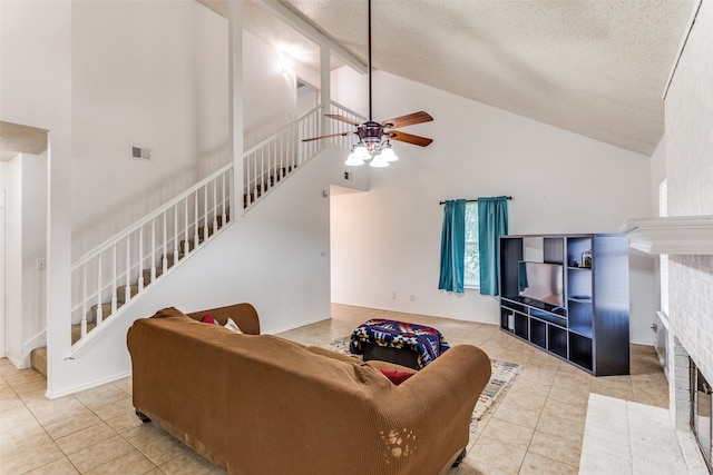 living room with a fireplace, a textured ceiling, light tile patterned floors, high vaulted ceiling, and ceiling fan