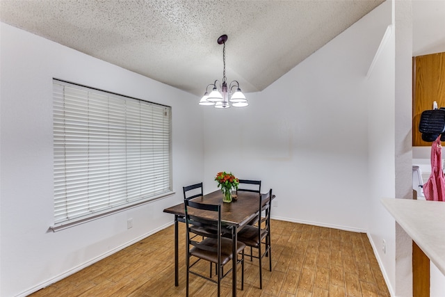 dining room with wood-type flooring, a textured ceiling, and an inviting chandelier