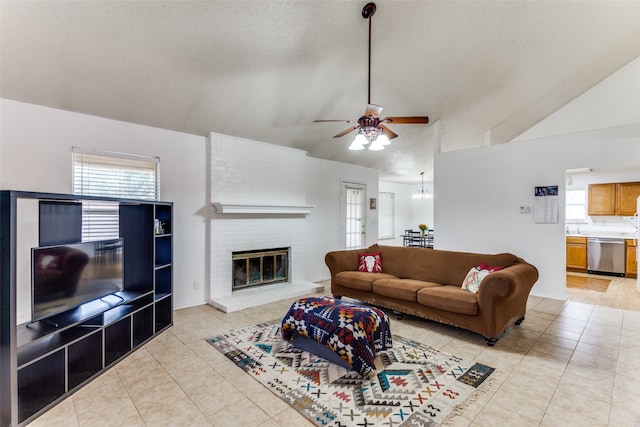 living room with ceiling fan, a textured ceiling, light tile patterned floors, high vaulted ceiling, and a fireplace