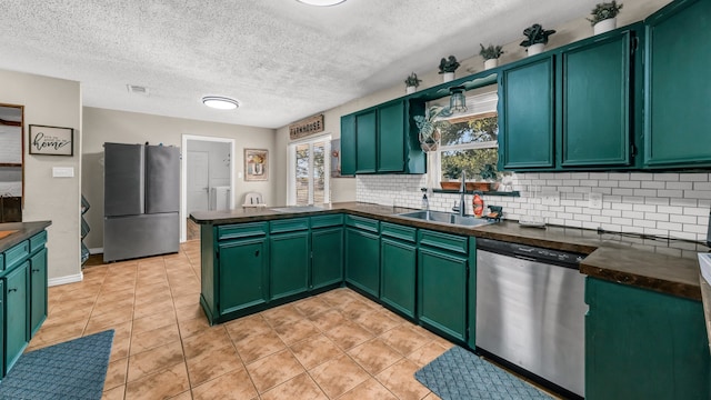 kitchen with tasteful backsplash, stainless steel appliances, green cabinets, sink, and kitchen peninsula