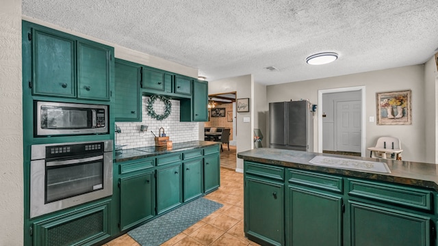 kitchen with green cabinets, a textured ceiling, and appliances with stainless steel finishes