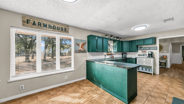 kitchen with backsplash, kitchen peninsula, green cabinets, and a healthy amount of sunlight