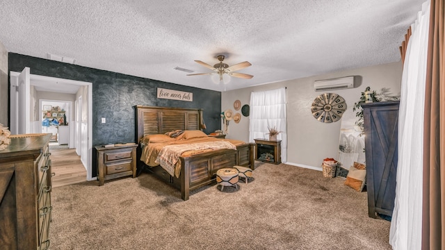 bedroom with a textured ceiling, a wall unit AC, carpet floors, and ceiling fan