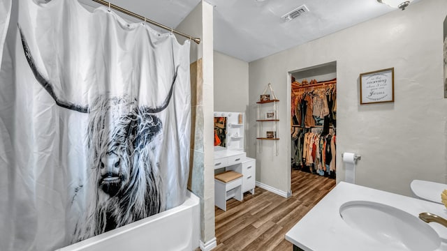 bathroom with wood-type flooring, vanity, and shower / bathtub combination with curtain