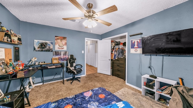 carpeted home office featuring a textured ceiling and ceiling fan