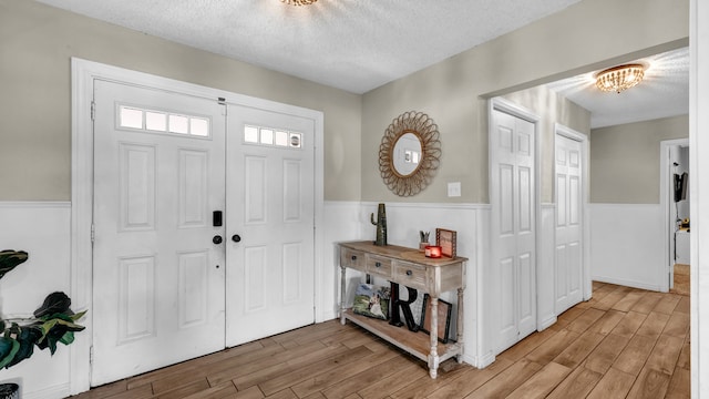 entryway with a chandelier, wood-type flooring, and a textured ceiling