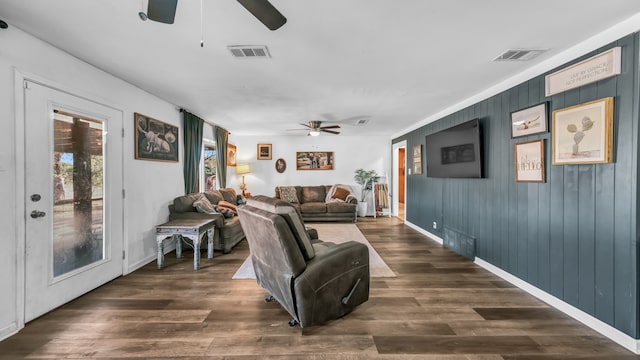 living room with wood walls, dark hardwood / wood-style floors, and ceiling fan