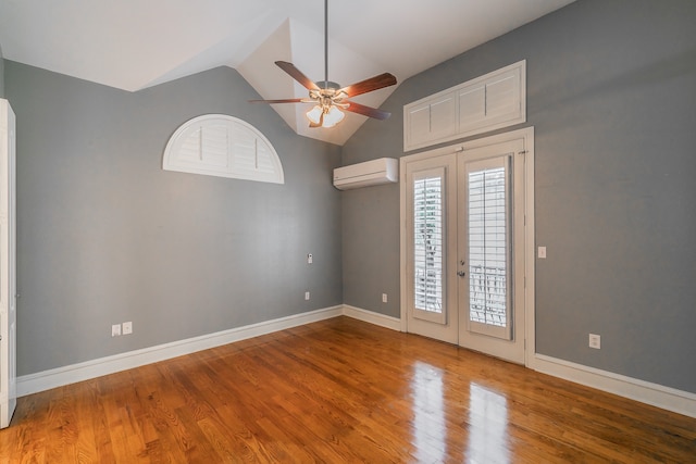 empty room featuring french doors, hardwood / wood-style floors, a wall unit AC, and ceiling fan