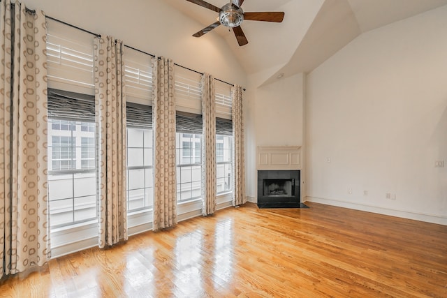 unfurnished living room with high vaulted ceiling, light hardwood / wood-style floors, ceiling fan, and a tile fireplace