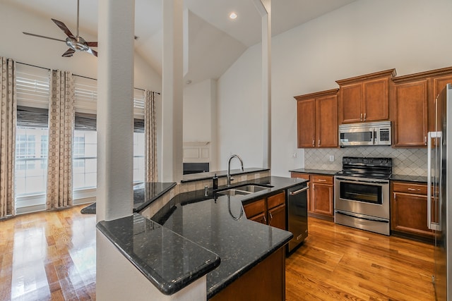 kitchen featuring light hardwood / wood-style flooring, sink, high vaulted ceiling, backsplash, and appliances with stainless steel finishes