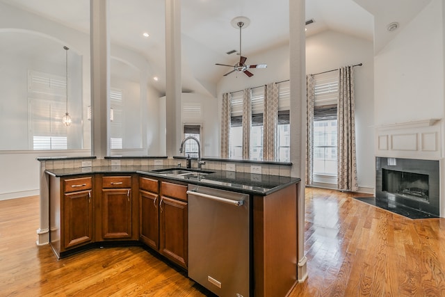 kitchen featuring stainless steel dishwasher, ceiling fan, dark stone countertops, and light hardwood / wood-style flooring