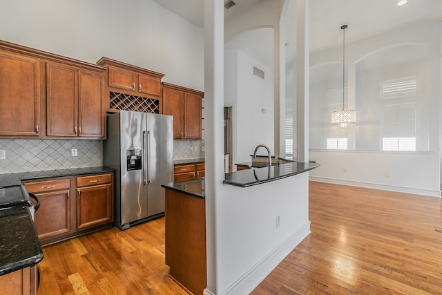 kitchen featuring hardwood / wood-style floors, hanging light fixtures, backsplash, and stainless steel fridge