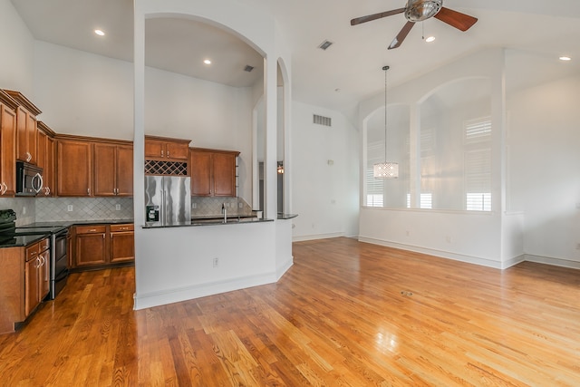 kitchen with appliances with stainless steel finishes, ceiling fan, backsplash, light hardwood / wood-style flooring, and pendant lighting