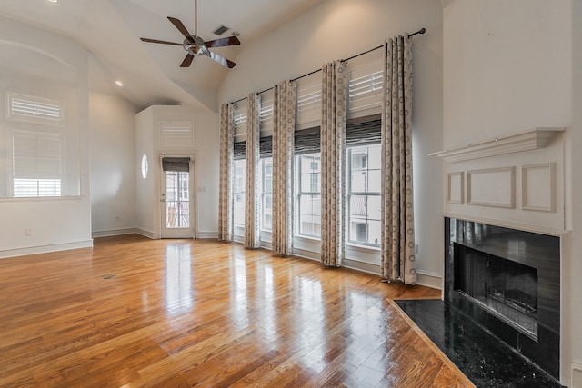 unfurnished living room with high vaulted ceiling, ceiling fan, a high end fireplace, and light hardwood / wood-style floors