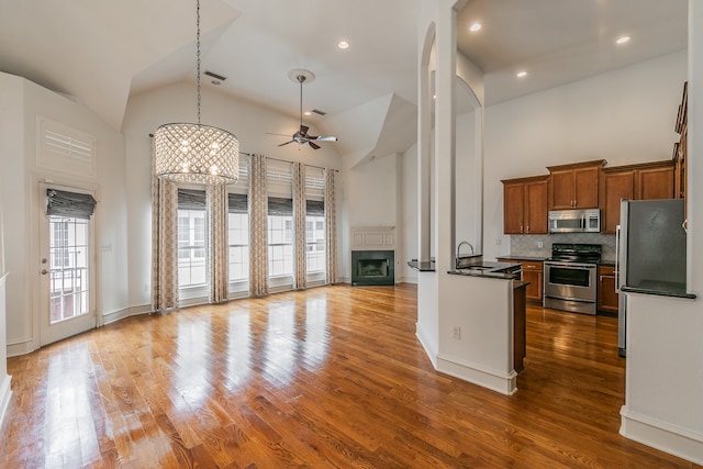 kitchen with stainless steel appliances, hardwood / wood-style floors, sink, high vaulted ceiling, and ceiling fan