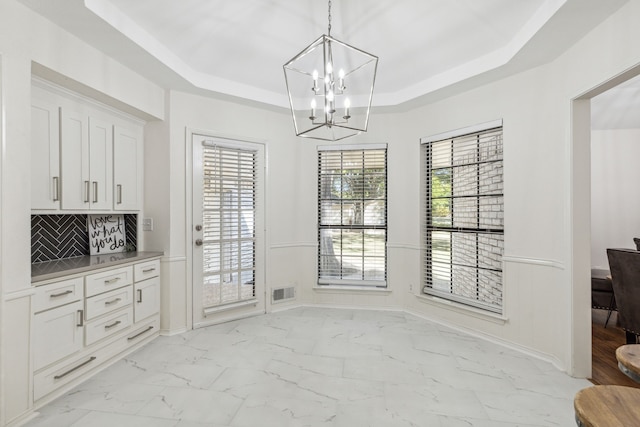 dining area featuring a chandelier and a raised ceiling