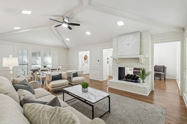 living room featuring lofted ceiling with beams, ceiling fan, a brick fireplace, and dark hardwood / wood-style flooring