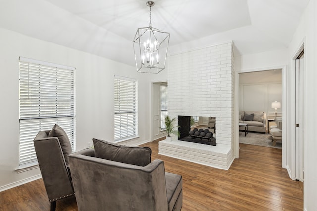 living room with dark wood-type flooring, an inviting chandelier, and a fireplace