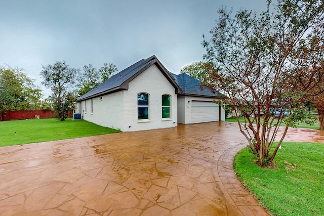 view of side of property with cooling unit, a garage, and a lawn