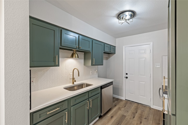 kitchen featuring sink, dishwasher, green cabinetry, decorative backsplash, and light wood-type flooring