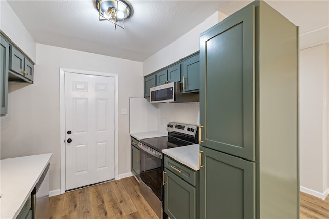 kitchen with green cabinets, light hardwood / wood-style flooring, and appliances with stainless steel finishes